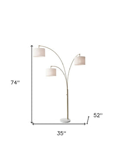 74" Brass Three Light Arc Floor Lamp With Off White Fabric Drum Shade