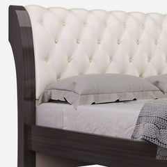 Solid wood king bed with tufted beige faux leather headboard and nailhead trim, featuring a sleek design and soft bedding.