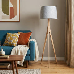 59" Natural Solid Wood Tripod Floor Lamp with Gray Fabric Empire Shade, placed next to a teal sofa with colorful cushions.