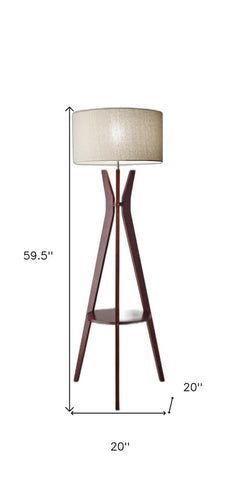 60" brown and white solid wood tripod floor lamp with a white fabric drum shade and a lower shelf for storage.