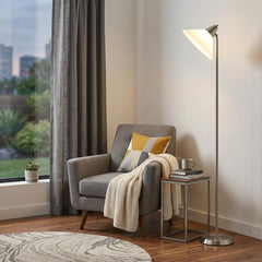 72" Silver floor lamp with white plastic shade, beside a gray armchair and small side table in a cozy living room setting.