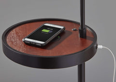 Beige and black tray table floor lamp with a beige fabric drum shade and a wooden tray for charging devices.