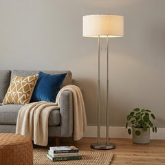 62" Silver Metal Task Floor Lamp with White Fabric Drum Shade beside a cozy sofa, featuring decorative pillows and a plant.