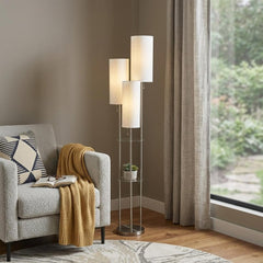 68" Silver Three Light Novelty Floor Lamp with White Linen Cylinder Shade beside a cozy armchair and a window.