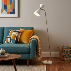 59" Gold and White Task Floor Lamp with a white metal cone shade, positioned next to a teal sofa with colorful pillows.