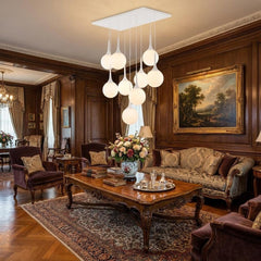 Dimmable white shaded nine light metal ceiling light hanging in an elegant living room with vintage decor and floral arrangem