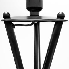 Black tripod floor lamp featuring a white fabric drum shade, showcasing a close-up of the base and legs.