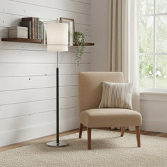 62" Floor Lamp with white fabric drum shade beside a beige chair with a striped pillow, set against a light wooden wall.