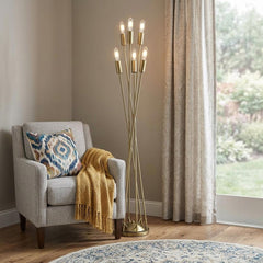 60" Six Light Torchiere Floor Lamp with a modern gold design, beside a cozy chair and decorative throw blanket.