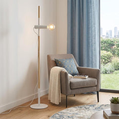 55" Brown and white reading floor lamp with a minimalist design, featuring a wooden pole and a round base, beside a cozy armc