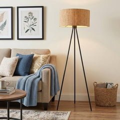 58" brown and black metal tripod floor lamp with a brown shade, placed next to a beige sofa in a cozy living room setting.