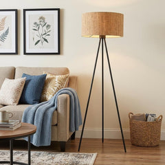 58" brown and black metal tripod floor lamp with a brown shade, placed next to a beige sofa with decorative pillows and a thr