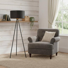 58" Matte Tripod Floor Lamp with Black Drum Shade beside a gray armchair on a textured rug in a bright room with wooden accen