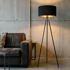 58" Matte Tripod Floor Lamp with Black Drum Shade, featuring a sleek design beside a brown leather sofa in a modern setting.