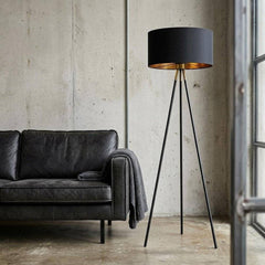 58" Matte Tripod Floor Lamp with Black Drum Shade, featuring a sleek design and gold interior, beside a modern sofa.