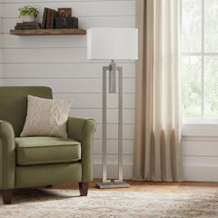 64" Nickel Traditional Floor Lamp with a white rectangular shade, standing beside a green armchair in a cozy room setting.
