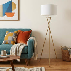 65" Gold and White Tripod Floor Lamp with a white fabric drum shade, set beside a teal sofa with colorful pillows and a coffe