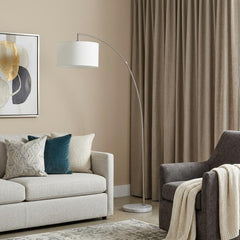 86" White and Silver Arc Floor Lamp with White Drum Shade, featuring a sleek design, complements a cozy living room setting.