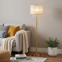 65" gold and white novelty floor lamp with a white fabric drum shade and decorative crystal accents, placed beside a cozy sof