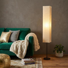 63" black and off-white column floor lamp with a rectangular off-white paper shade, illuminating a cozy living space.