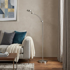 54" Silver Adjustable LED Task Floor Lamp with a sleek design, featuring a curved arm and a round base, placed beside a cozy 