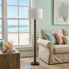 61" brown and white resin floor lamp with a white fabric drum shade, placed beside a light-colored sofa in a beachside settin
