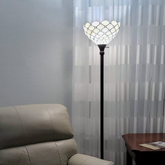 62" brown and white floor lamp with a white glass bowl shade, placed next to a cream-colored chair and a wooden table.