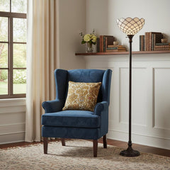 62" brown and white floor lamp with a white glass bowl shade beside a blue armchair with a decorative pillow in a cozy room.