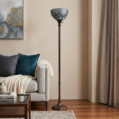 62" brown and white torchiere floor lamp with a white peacock feather glass dome shade, standing beside a cozy sofa.