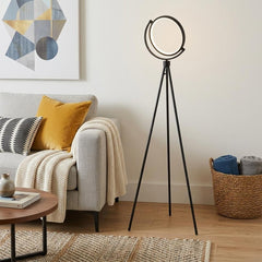 60" Black LED Tripod Floor Lamp with a sleek black metal shade, illuminating a cozy living room setting with a modern design.