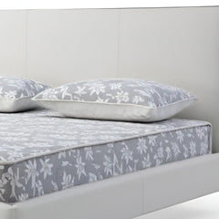White wood and faux leather king bed frame featuring a sleek design and integrated USB ports, with a floral-patterned mattres