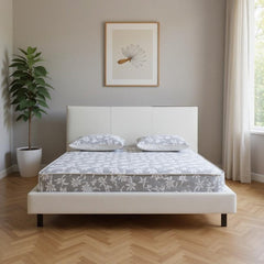 White wood and faux leather king bed frame with USB ports, featuring a minimalist design and two pillows on a patterned mattr