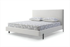 White wood and faux leather king bed frame with USB, featuring a sleek design and two pillows on a patterned mattress.