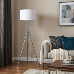 64" Silver Adjustable Tripod Floor Lamp with White Fabric Shade, featuring a modern design beside a cozy sofa and decorative 