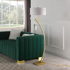 59" Gold and White Arc Floor Lamp featuring a white fabric drum shade, positioned beside a green velvet sofa.