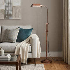 57" rusted adjustable floor lamp with a traditional shape and rust square shade, placed beside a cozy sofa with decorative pi