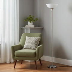 70" Nickel Metal Torchiere Floor Lamp with a white glass dome shade beside a green armchair in a cozy room setting.