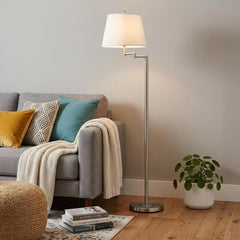60" Nickel Swing Arm Floor Lamp with White Square Shade, featuring a sleek design beside a cozy sofa with decorative pillows.