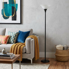71" Black Torchiere Floor Lamp with Black Glass Dome Shade, positioned next to a cozy sofa with colorful cushions and a throw