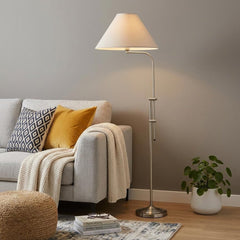 68" Nickel Adjustable Floor Lamp with White Fabric Empire Shade beside a gray sofa, featuring a cozy throw and a potted plant