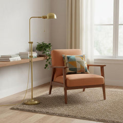 58" Brass Adjustable Floor Lamp with Bronze Dome Shade beside a cozy orange armchair and a wooden shelf with books.
