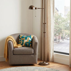 58" rust metal adjustable swing arm floor lamp with dome shade beside a cozy armchair and window, featuring a colorful pillow