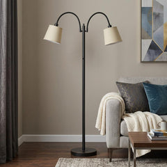 65" Bronze Two Light Traditional Floor Lamp with tan square shades, featuring a curved design and placed beside a cozy sofa.