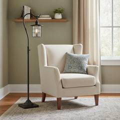 60" Antiqued Bronze Lantern Style Floor Lamp with glass and metal shade beside a cozy armchair in a well-lit room.