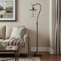60" rusted traditional floor lamp with a rust transparent glass drum shade, standing beside a sofa in a cozy living room sett