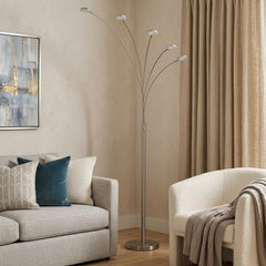 72" Nickel Five Light LED Arc Floor Lamp with curved arms, modern design, placed next to a cozy sofa and draped throw.