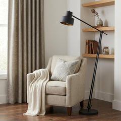 65" black adjustable floor lamp with a traditional shape and black dome shade, positioned next to a cozy armchair and shelves