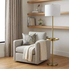62" Brass Tray Table Floor Lamp with White Square Shade beside a cozy armchair, featuring a decorative pillow and a throw bla