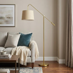 68" Brass Adjustable Traditional Floor Lamp with Antiqued Brass Drum Shade, featuring a sleek design beside a cozy sofa.