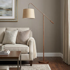 68" rusted adjustable floor lamp with a rust drum shade, positioned next to a beige sofa in a cozy living room setting.